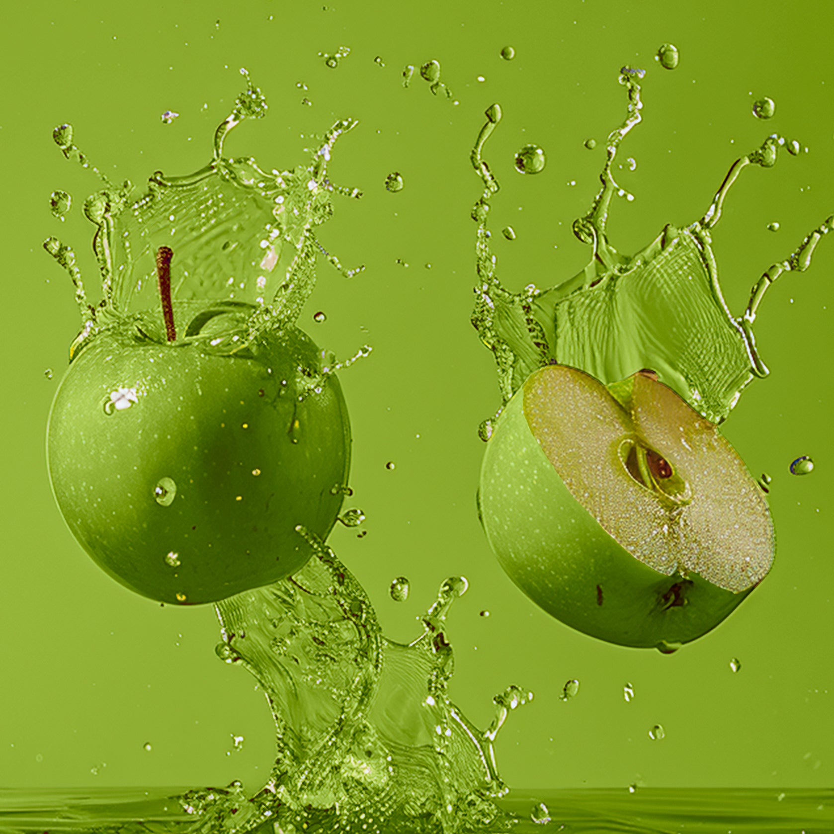 Accord de pommes verte. Photographie de deux pommes vertes, l'une entière et l'autre coupée en deux, avec des gouttelettes d'eau suggérant de la fraîcheur du fruit. 